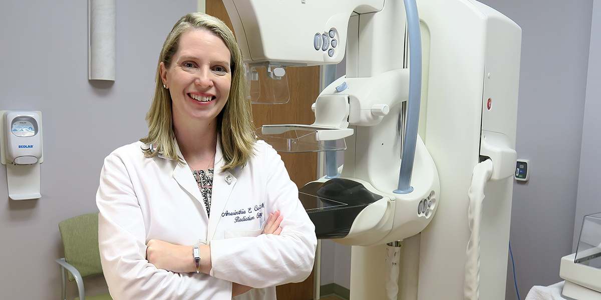 Radiation oncologist Amy Curtis, MD, poses with a 3D mammography machine that she uses for research on a clinical trial at Gibbs Cancer Center..