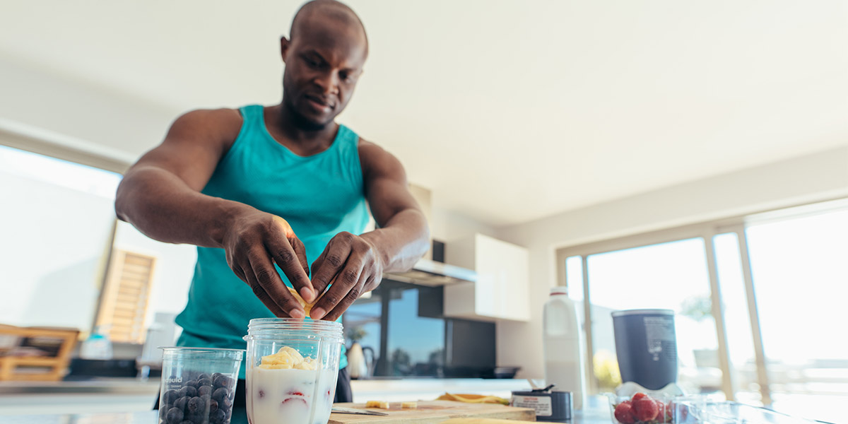 An athletic man adds healthy fruit into his smoothie to optimize his diet for sports performance.