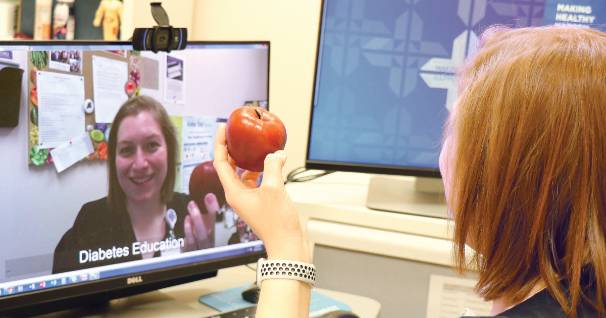 Julia Savoy, diabetes educator, poses holding an apple in front of a computer to demonstrate how a telediabetes education visit helps to reach the local community at Spartanburg Regional Healthcare System's Union Medical Center.
