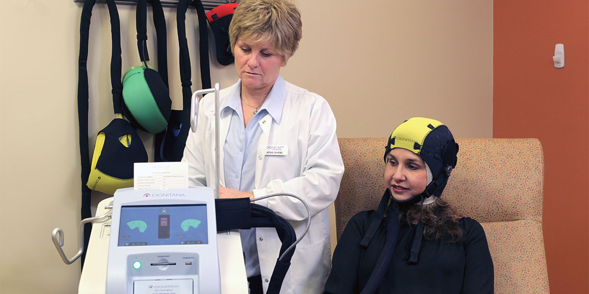 a doctor monitors a patient wearing the DigniCap Scalp Cooling System