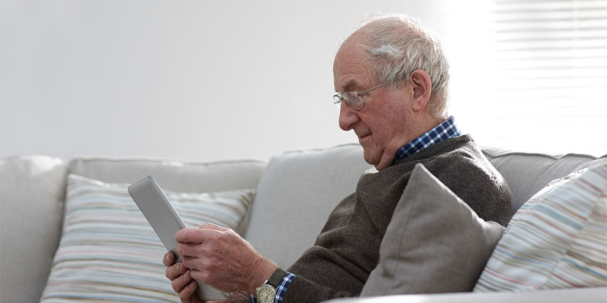 Senior man sitting on sofa using digital tablet