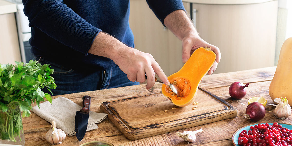 Man cooking healthy food of a pumpkin on a wooden table in a home kitchen