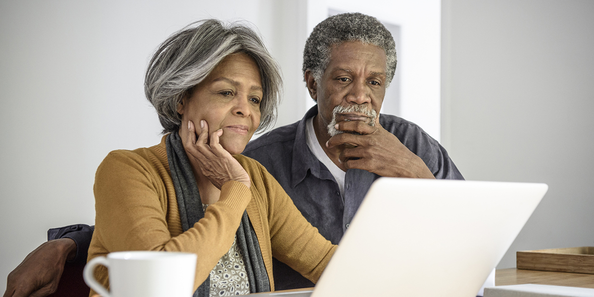 Senior African American couple using laptop, contemplating