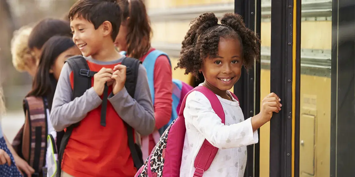 Elementary school girl at the front of the school bus queue